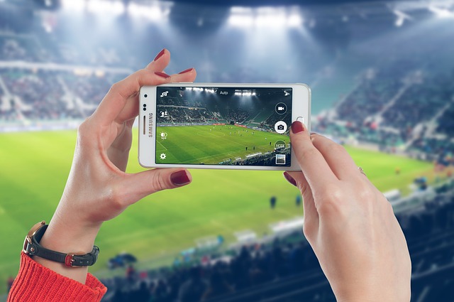 žena s mobilem na stadionu
